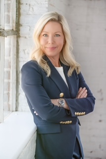 A woman in a blue suit with her arms crossed.