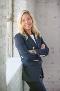 A woman in a suit standing with her arms crossed.